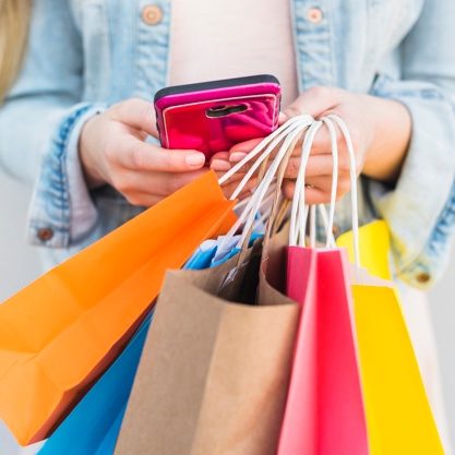 woman-with-bright-shopping-bags-using-smartphone_23-2148042888